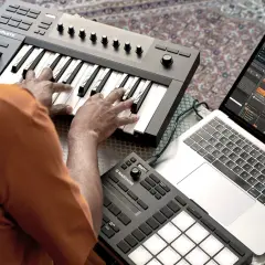 Ein beat producer arbeitet an seinem Laptop mit Musiksoftware und spielt auf einem MIDI-Keyboard.