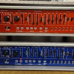 Zwei R-101 Synthesizer-Module, rot und blau, mit vielen Reglern und Schiebereglern für die Klangerzeugung. Das Din Sync Logo ist gut sichtbar.