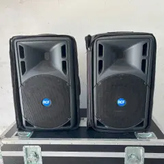 Zwei RCF 322a Lautsprecher in Schutzhüllen stehen auf einem schwarzen Flightcase.