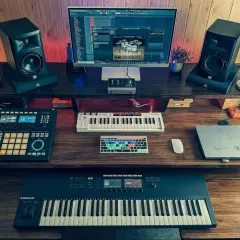 Ein Studio-Setup für einen Rap Beat Maker mit zwei Monitoren, Keyboards, Pads und Lautsprechern.