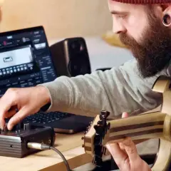 Mann mit Bart spielt Gitarre und bedient ein Audio-Interface, während er auf einem Laptop mit der **ToneX**-Software arbeitet.