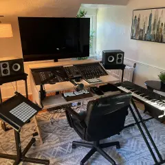 Ein Studio für Musikproduktion mit Mischpult, Keyboard, Mikrofon und Lautsprechern.