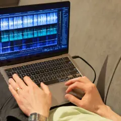 Person bearbeitet Audio-Spuren auf einem Laptop mit der rx connect app.
