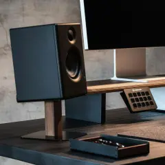 Schwarzer Lautsprecher auf einem schlichten Holzständer, Teil eines DIY-Lautsprecherständer-Projekts. Daneben ein Monitor und ein Stream Deck.