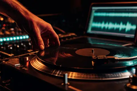 Hand legt Vinyl auf Plattenspieler, Laptop zeigt Wellenform. Perfekt für Vinyl Mastering.