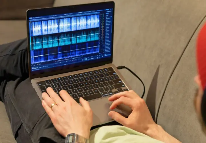 Person bearbeitet Audio-Spuren auf einem Laptop mit der rx connect app.