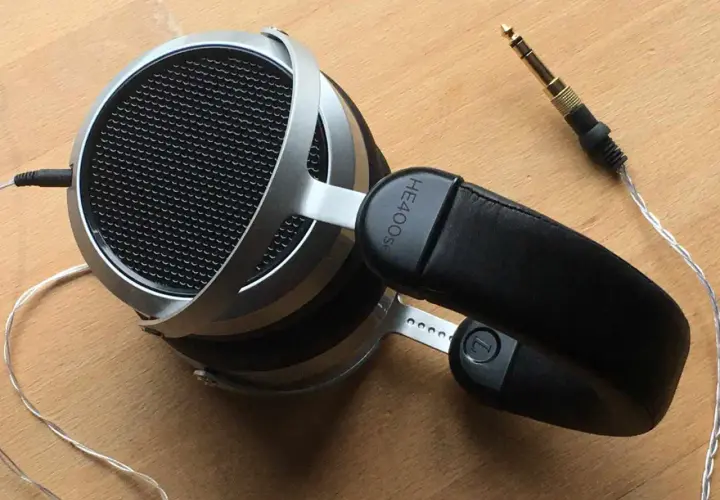 Hifiman HE400SE Test: Offene Kopfhörer mit silbernem Bügel und schwarzem Leder-Kopfband. Der 3,5mm Klinkenstecker liegt daneben.