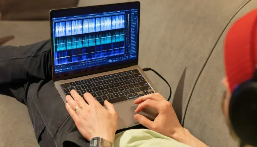 Person bearbeitet Audio-Spuren auf einem Laptop mit der rx connect app.