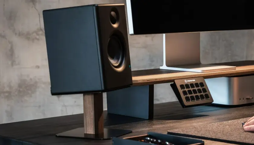 Schwarzer Lautsprecher auf einem schlichten Holzständer, Teil eines DIY-Lautsprecherständer-Projekts. Daneben ein Monitor und ein Stream Deck.