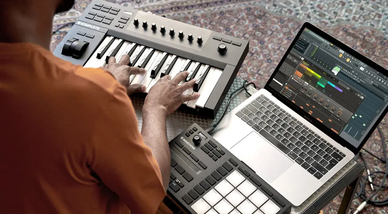 Ein beat producer arbeitet an seinem Laptop mit Musiksoftware und spielt auf einem MIDI-Keyboard.