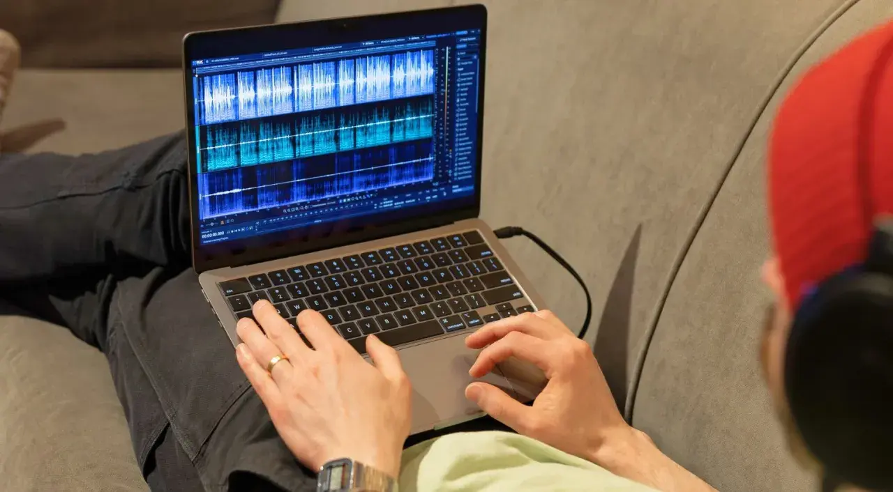 Person bearbeitet Audio-Spuren auf einem Laptop mit der rx connect app.