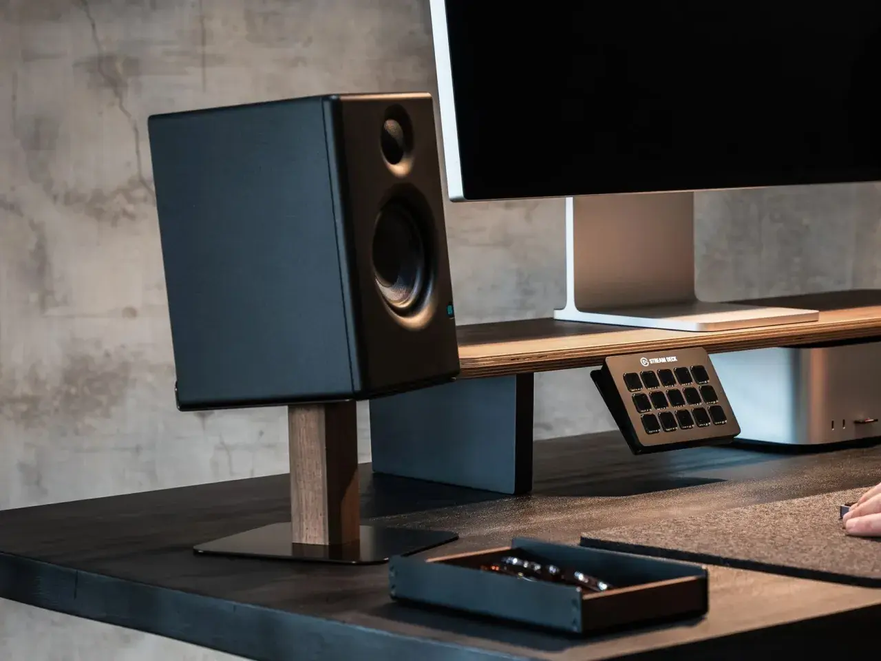 Schwarzer Lautsprecher auf einem schlichten Holzständer, Teil eines DIY-Lautsprecherständer-Projekts. Daneben ein Monitor und ein Stream Deck.