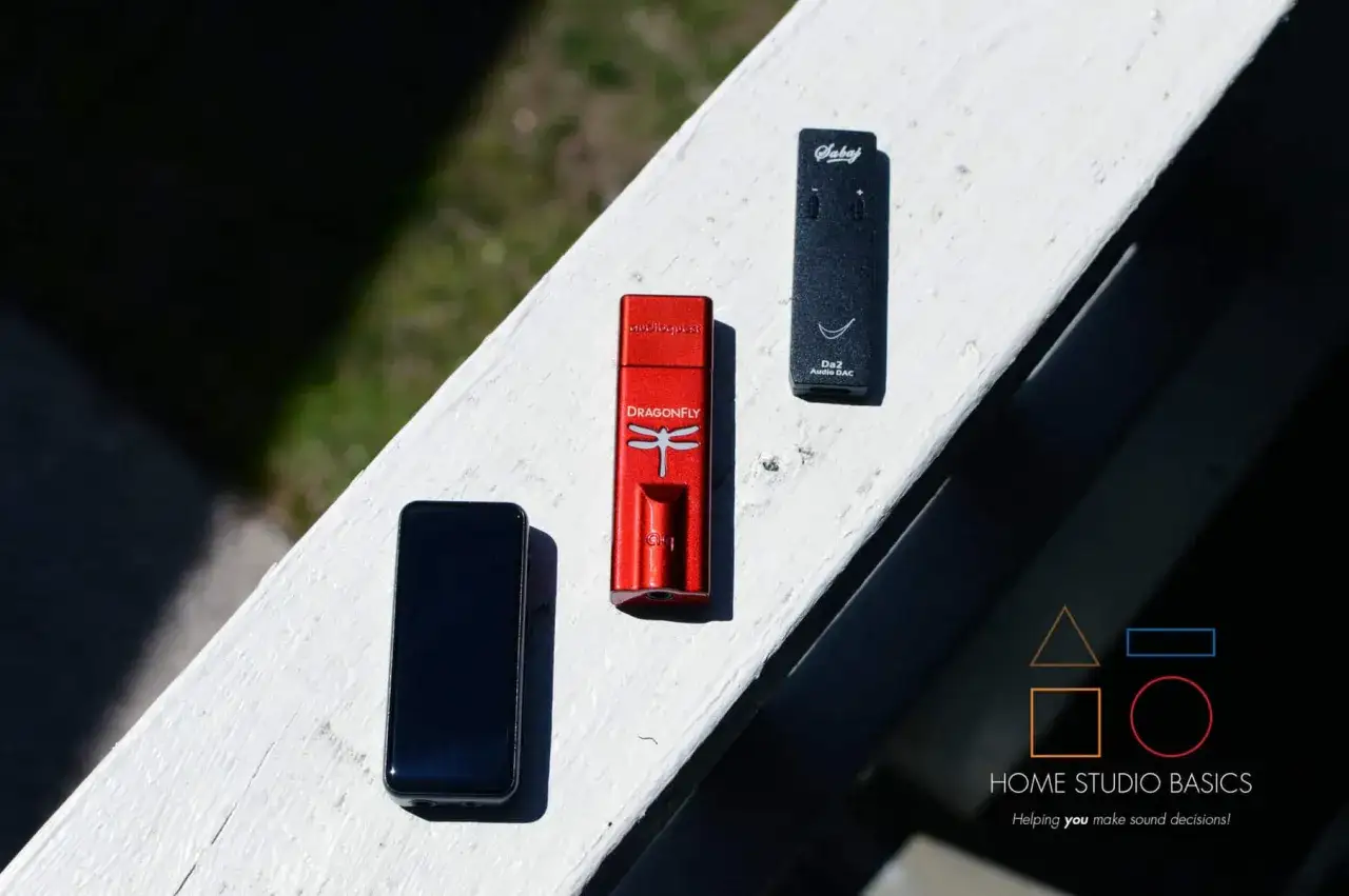 Drei Audio-DACs: ein schwarzes Smartphone, ein roter AudioQuest Dragonfly und ein schwarzer Sabaj Da2. Welcher hat den besten DAC-Chip?