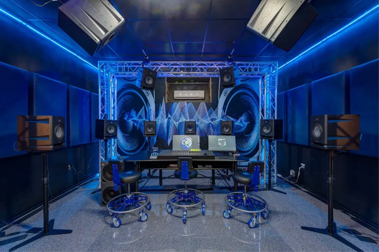 Professionelle Studio-Einrichtung mit vielen Lautsprechern und einem Mischpult, ideal für Mixing-Tipps. Blaue Beleuchtung schafft eine coole Atmosphäre.