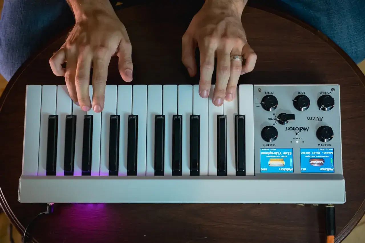 Hände spielen auf einem Mellotron-Instrument. Die Tasten leuchten lila.